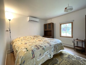 A bedroom with a bed, an air conditioning unit, a window, a cabinet, and a floor lamp. - 2 Person Holiday Home in Norrkoping (Norrköping)