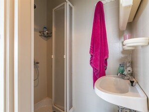 A bathroom with a shower, a sink, and a pink towel hanging on the wall. - Studio Apartment in Seaside With Panoramic Views (Middelkerke)