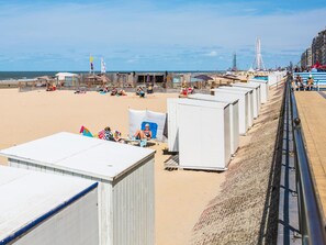 A beachside hotel with multiple white cabins, a sandy beach, and a Ferris wheel in the background. - Studio Apartment in Seaside With Panoramic Views (Middelkerke)