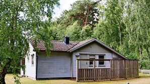 Un bâtiment d’un seul étage, doté d’un toit à pignon, d’une cour clôturée et d’une clôture en bois à l’avant.