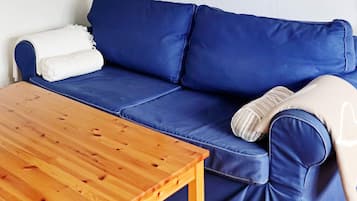 A blue sofa with a white throw blanket and a wooden table.