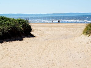 A sandy beach path leading to the ocean with two people walking. - 5 Person Holiday Home in Skummeslovsstrand (Skummesloevsstrand)