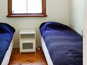 A small room with two single beds, a white nightstand, and a window. - 5 Person Holiday Home in Skummeslovsstrand (Skummesloevsstrand)