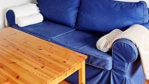 Un sofá azul con un plaid blanco y una mesa de madera.