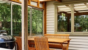An outdoor patio with a wooden table and chairs, large windows, and a grill. - 5 Person Holiday Home in Skummeslovsstrand (Skummesloevsstrand)