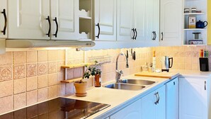 A kitchen with white cabinets, a black countertop, and a tiled backsplash. - 4 Star Holiday Home in Sturko (Sturkö)