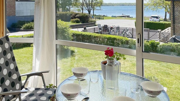 A glass table with bowls and a vase, overlooking a lake and park. - 4 Star Holiday Home in Sturko (Sturkö)