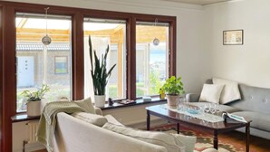 A living room with a sofa, a coffee table, and two potted plants. - 4 Star Holiday Home in Sturko (Sturkö)