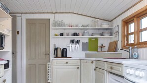 A compact kitchen with white cabinetry, a stove, and various kitchen utensils and appliances.