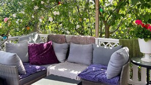 A wicker sofa with cushions, a small table, and a potted plant on an outdoor patio. - 4 Person Holiday Home in Arsta Havsbad (Haninge)