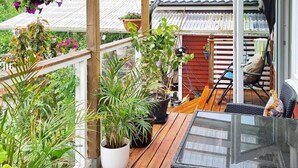 A wooden deck with potted plants, a glass table, and outdoor furniture. - 4 Person Holiday Home in Arsta Havsbad (Haninge)
