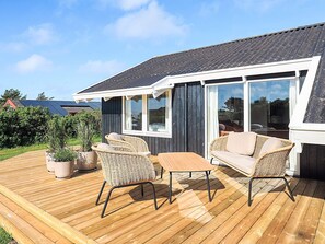 A wooden deck with wicker furniture, a table, and potted plants. - 4 Star Holiday Home in Hjorring (Hjørring)