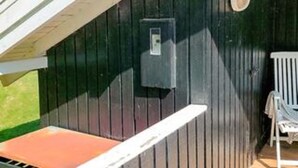 Un mur extérieur en bois foncé, avec une porte blanche et une petite fenêtre.