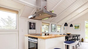 Une cuisine moderne dotée d’un îlot central, d’un four encastré et d’un coin repas avec des chaises et une table.