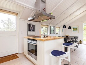 Une cuisine moderne dotée d’un îlot central, d’un four encastré et d’un coin repas avec des chaises et une table.
