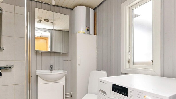 A compact bathroom with a toilet, sink, and washing machine.