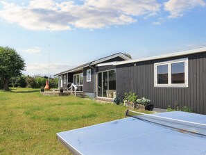 A residential property with a tennis court, a house with a porch, and a large tree. - 4 Person Holiday Home in Karrebaeksminde (Karrebæksminde)