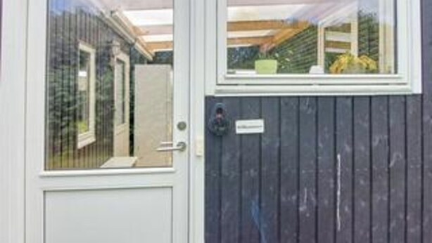 Eine Tür mit Fenster, einem Schild und einem Holzzaun.