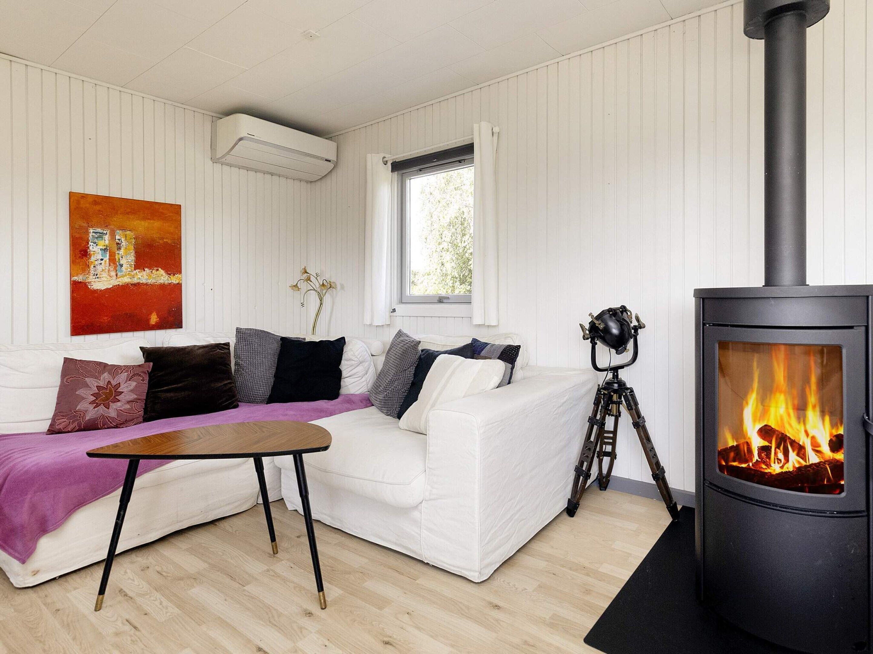 A cozy living room with a white sofa, a small table, and a black wood-burning stove.