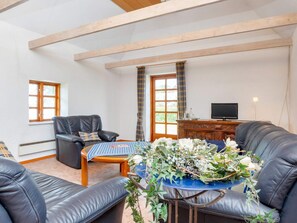 A living room with a sofa, a chair, a coffee table, and a television on a wooden cabinet.