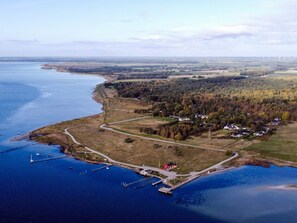 An aerial view of a coastal area with a marina, a winding road, and scattered houses.