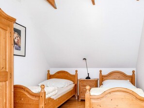 A bedroom with two wooden beds, a nightstand, a lamp, and a framed picture on the wall. - 8 Person Holiday Home in Hadsund (Hadsund)