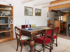 A dining area with a wooden table, chairs, and a bookshelf.