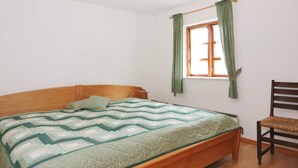 A single bed with a wooden headboard, a green and white patterned bedspread, and a wooden chair to the right. - 8 Person Holiday Home in Hadsund (Hadsund)