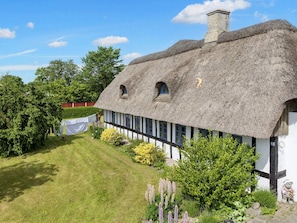 A thatched-roof house with a white exterior, a chimney, and a small window. - 8 Person Holiday Home in Hadsund (Hadsund)