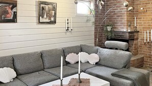 A modern living room with a grey sectional sofa, a white coffee table, and a brick fireplace. - 8 Person Holiday Home in Ingaro (Ingaro)
