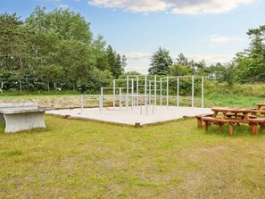 Une salle de sport en plein air équipée de matériel d’exercice, de tables de pique-nique et d’un banc en béton.