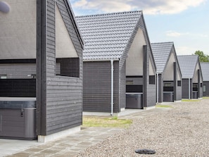 A row of modern buildings with grey roofs and dark siding, featuring large windows and a gravel pathway. - 5 Star Holiday Home in Romo (Rømø)