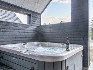 Un bain à remous, une bouteille de bière, des murs en bois et une fenêtre.