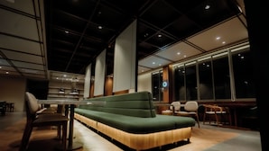 Un intérieur moderne avec un canapé vert, un plancher en bois et une grande fenêtre qui laisse entrer la lumière naturelle.