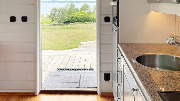 A kitchen with a view of a grassy area and trees. - 4 Star Holiday Home in Drottningskar (Drottningskär)