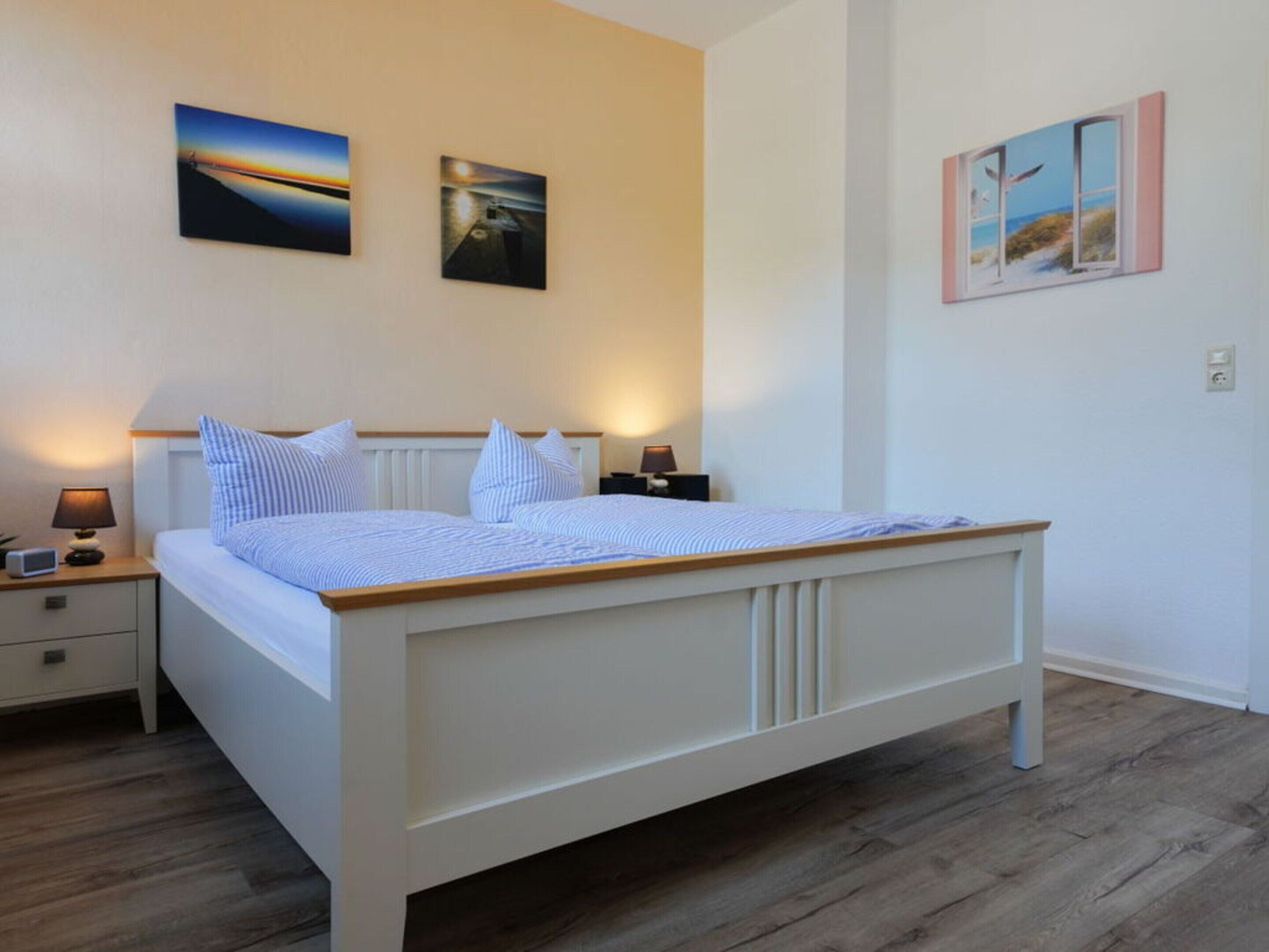 Un dormitorio con cama, mesitas de noche y decoración en la pared.