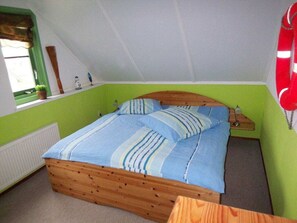 A bedroom with a wooden bed, green walls, a window with blinds, and a red telephone. - "sina" Comfortable Holiday Residence (Julianadorp)