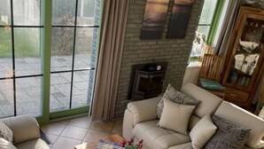 A living room with a sofa set, a coffee table with a vase, and a fireplace. - "sina" Comfortable Holiday Residence (Julianadorp)