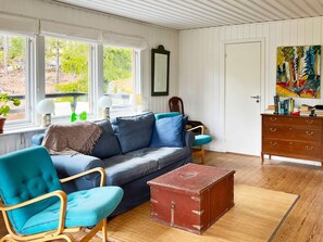 A cozy living room with a sofa, armchair, and a red trunk. - 4 Star Holiday Home in Vato (Vätö)