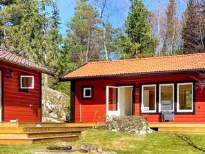 A red cabin with a tiled roof, a small porch, and a stone wall. - 4 Star Holiday Home in Vato (Vätö)