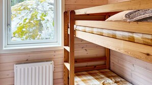 A bunk bed with a checkered bedspread, a window with a view of a rocky landscape, and a white radiator. - 4 Star Holiday Home in Vato (Vätö)