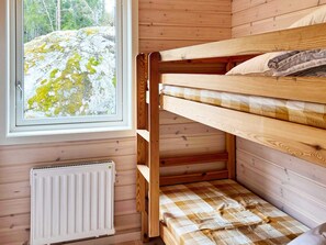 A bunk bed with a checkered bedspread, a window with a view of a rocky landscape, and a white radiator. - 4 Star Holiday Home in Vato (Vätö)