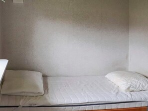 A small, single-bed room with a plain wall and a simple bed. - 4 Star Holiday Home in Mellbystrand (Mellbystrand)