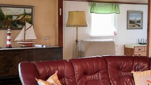A room with a leather sofa, a lamp, a small sailboat model, and a lighthouse model. - 4 Star Holiday Home in Mellbystrand (Mellbystrand)