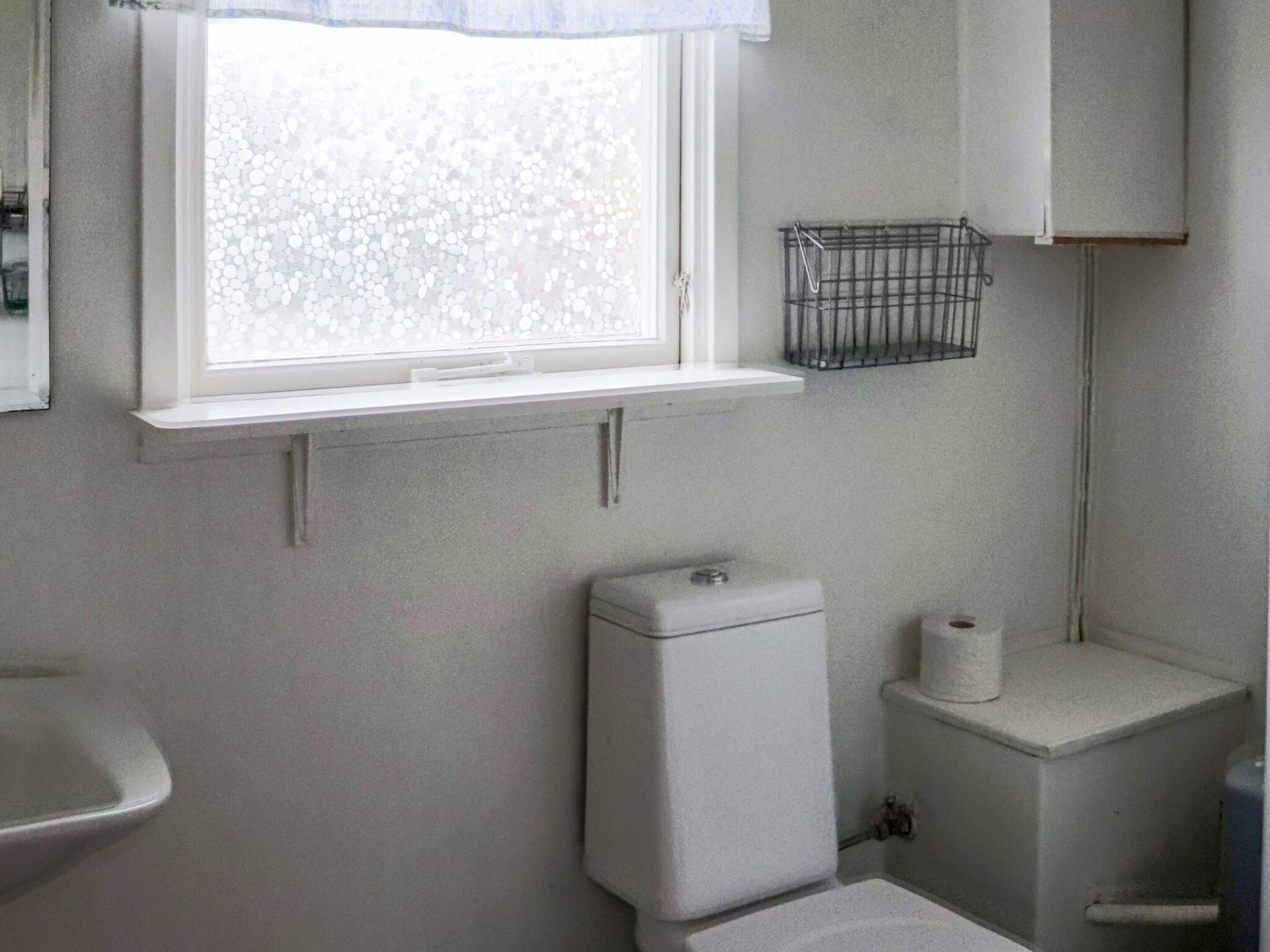 Un baño con inodoro, lavamanos y ventana.