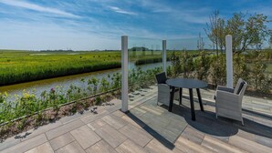 An outdoor seating area with a view of a river and fields. - Energy-neutral Villa for 2 People (Oudeschild)