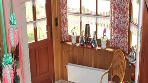 A cozy room with a wooden door, a radiator, a wicker chair, and a shelf with decorative items. - "haus Burck" Modern Retreat (Wankendorf)