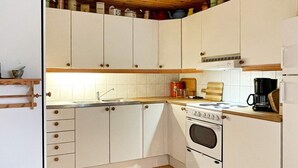 A kitchen with white cabinets, a wooden countertop, a stove, and a coffee maker. - 5 Person Holiday Home in Borgholm (Borgholm)