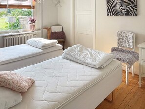 A bedroom with two single beds, a chair, a table, and a zebra-patterned artwork on the wall. - 4 Star Holiday Home in Solvesborg (Sölvesborg)