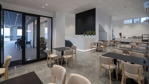 A modern conference room with glass walls, a reception area, and a dining space with tables and chairs. - Arrei Hotel (Sarandë)